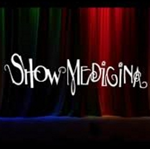 Símbolo do Show Medicina. O fundo da imagem é uma cortina de teatro preta fechada iluminada com luzes azuis e vermelhas. Ao centro, escrito Show Medicina em letras brancas