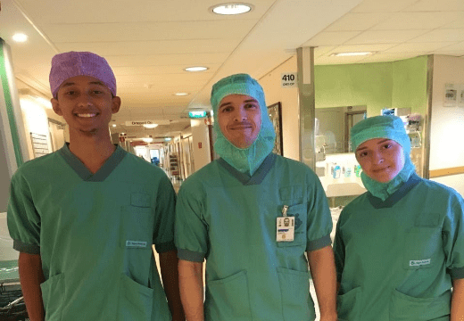 Foto de 3 pessoas com capote verde num hospital