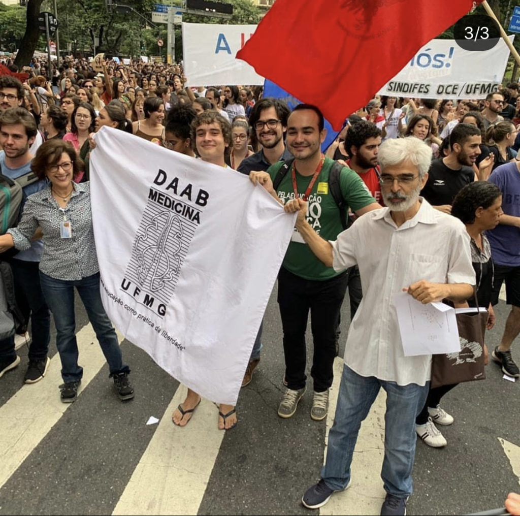 Foto de uma manifestação em maio de 2019, na foto, membros atuais do DAAB encontram com membros antigos e seguram a bandeira do diretório