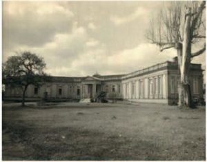 Fotografia em preto e branco do (hoje) ambulatório Borges da Costa, de 1922. A fotografia foi tirada de forma oblíqua do canto esquerdo da face anterior do prédio. Além do prédio se oobserva uma árvore sem folhas em cada cando da fachada.